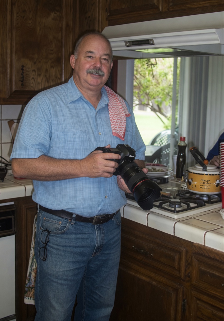 Mark Thomas Firestone holding a camera in a kitchen.