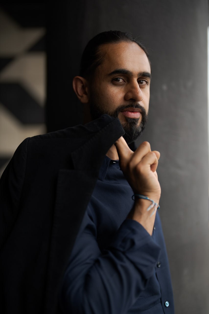 Moody portrait of a man in dark clothing near a window.
